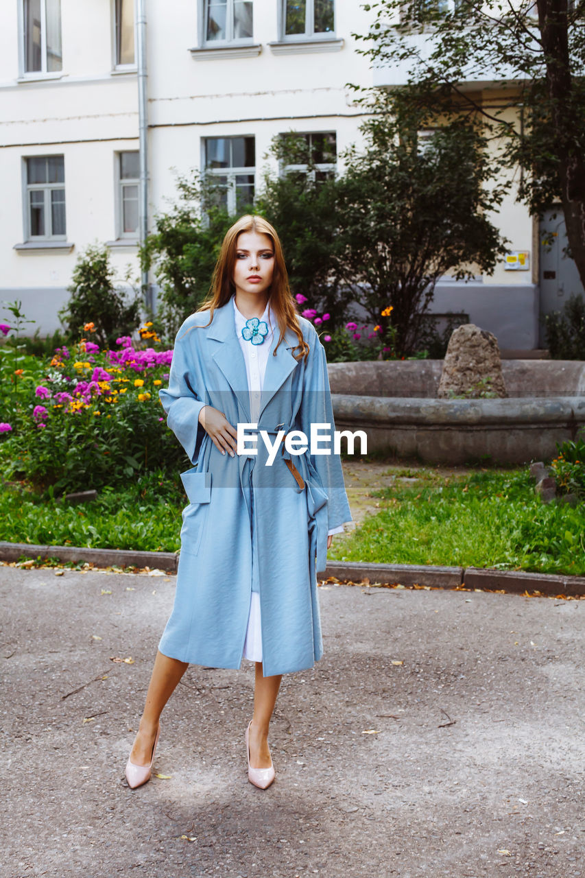 Fashionable young woman wearing blue overcoat at public park