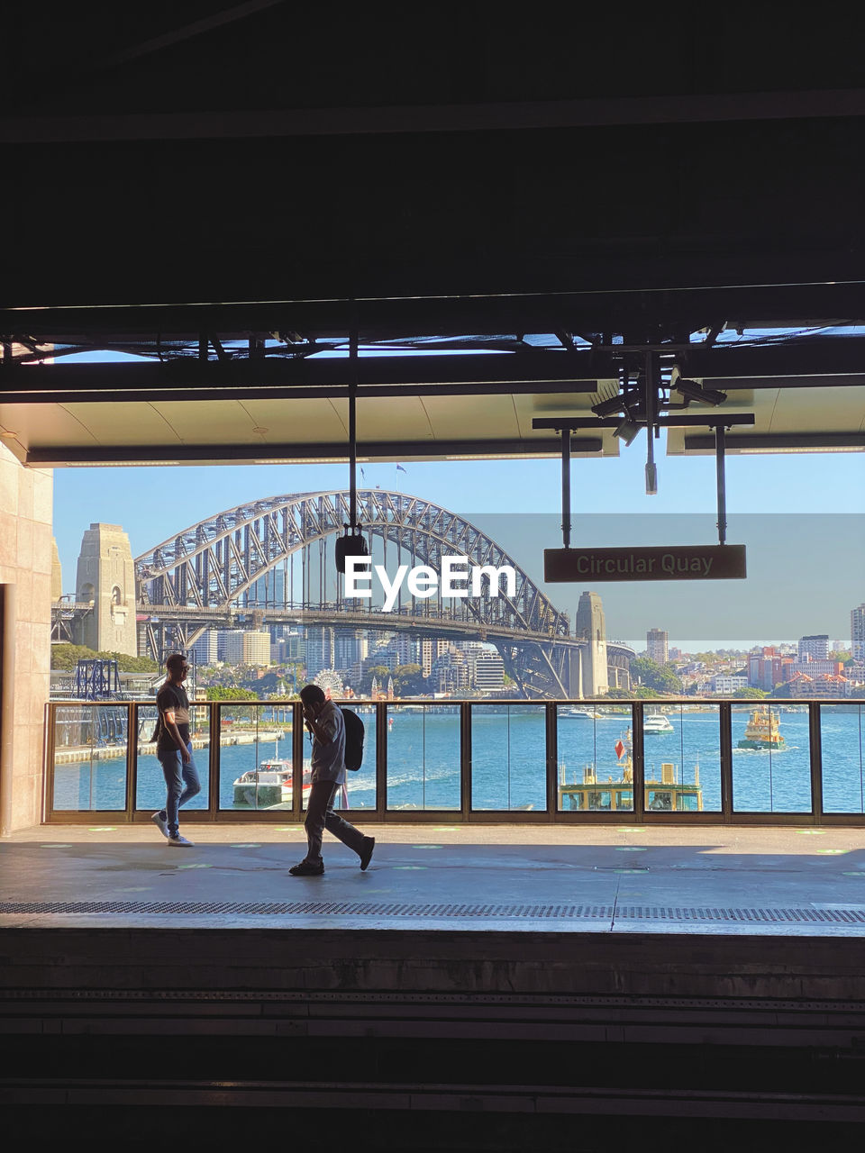 PEOPLE WALKING ON BRIDGE OVER CITY