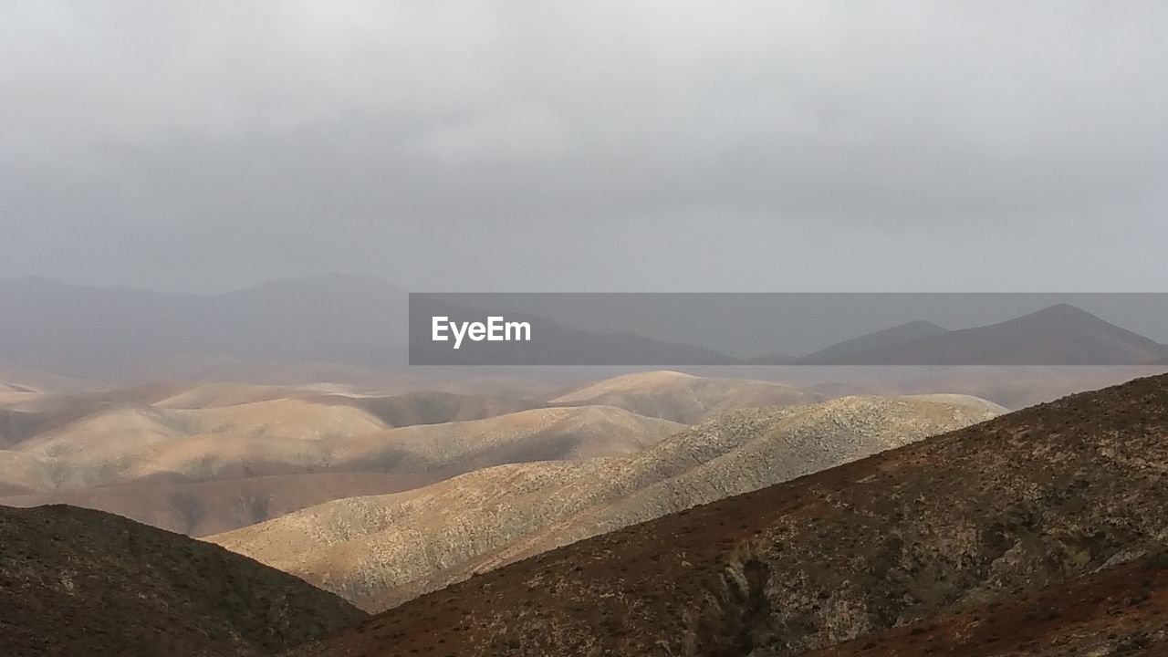 Scenic view of mountains against cloudy sky