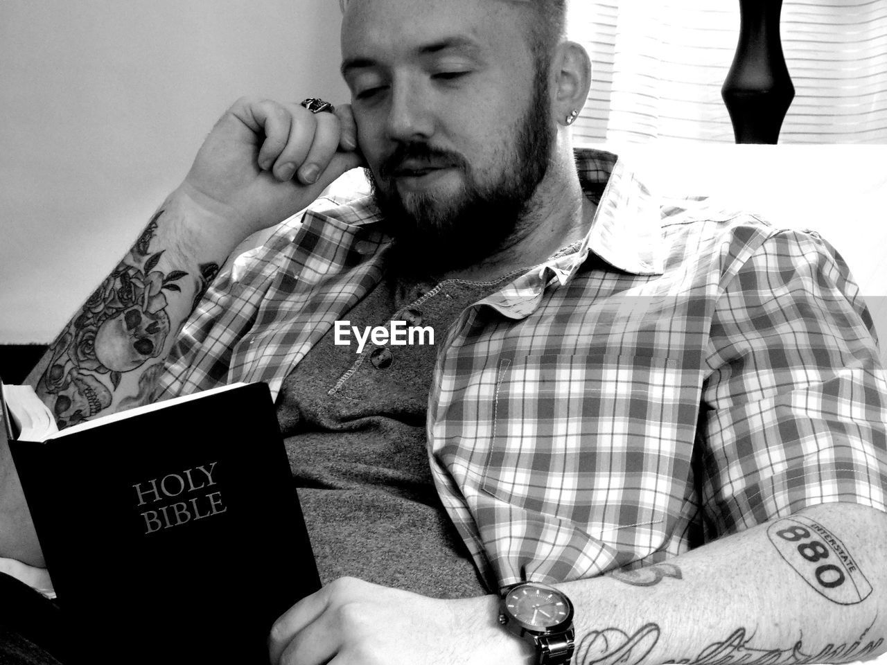 Man reading bible while sitting at home