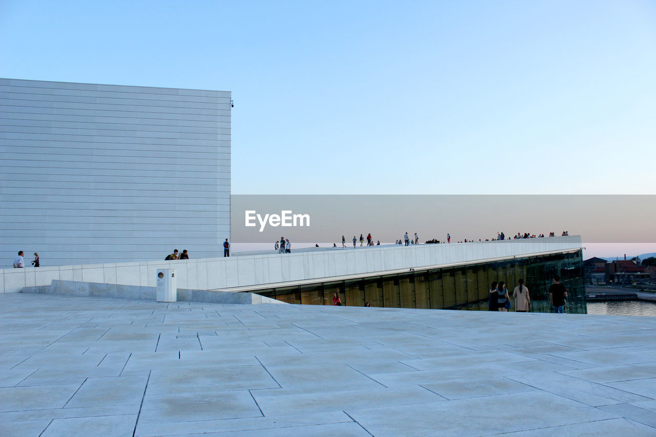 PEOPLE ON MODERN BUILDING AGAINST SKY