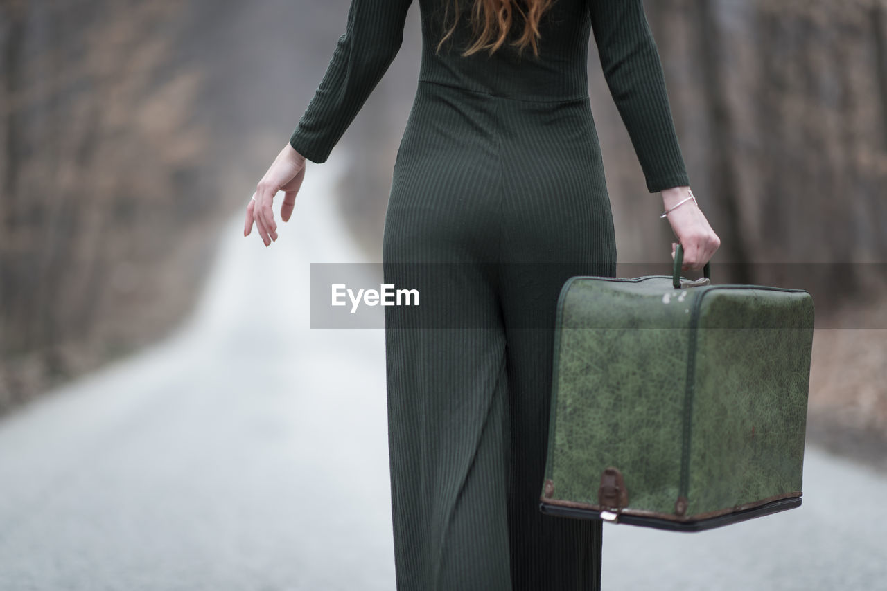 midsection of woman holding book while standing in park