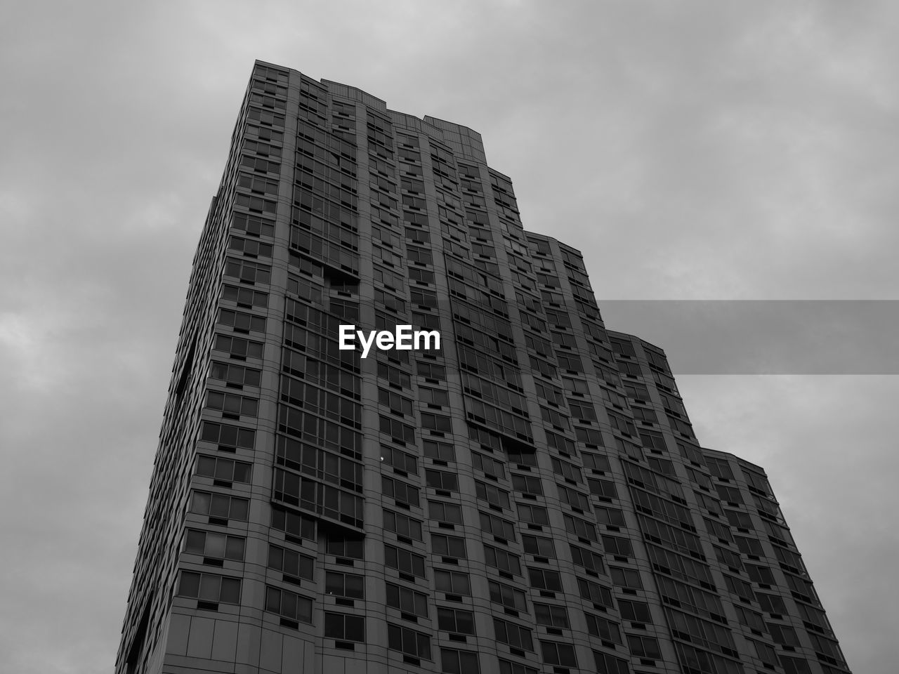 LOW ANGLE VIEW OF OFFICE BUILDING AGAINST CLOUDY SKY