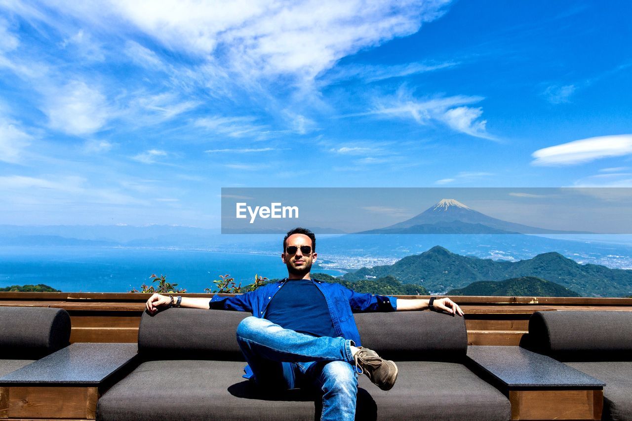 Portrait of man sitting on sofa against blue sky