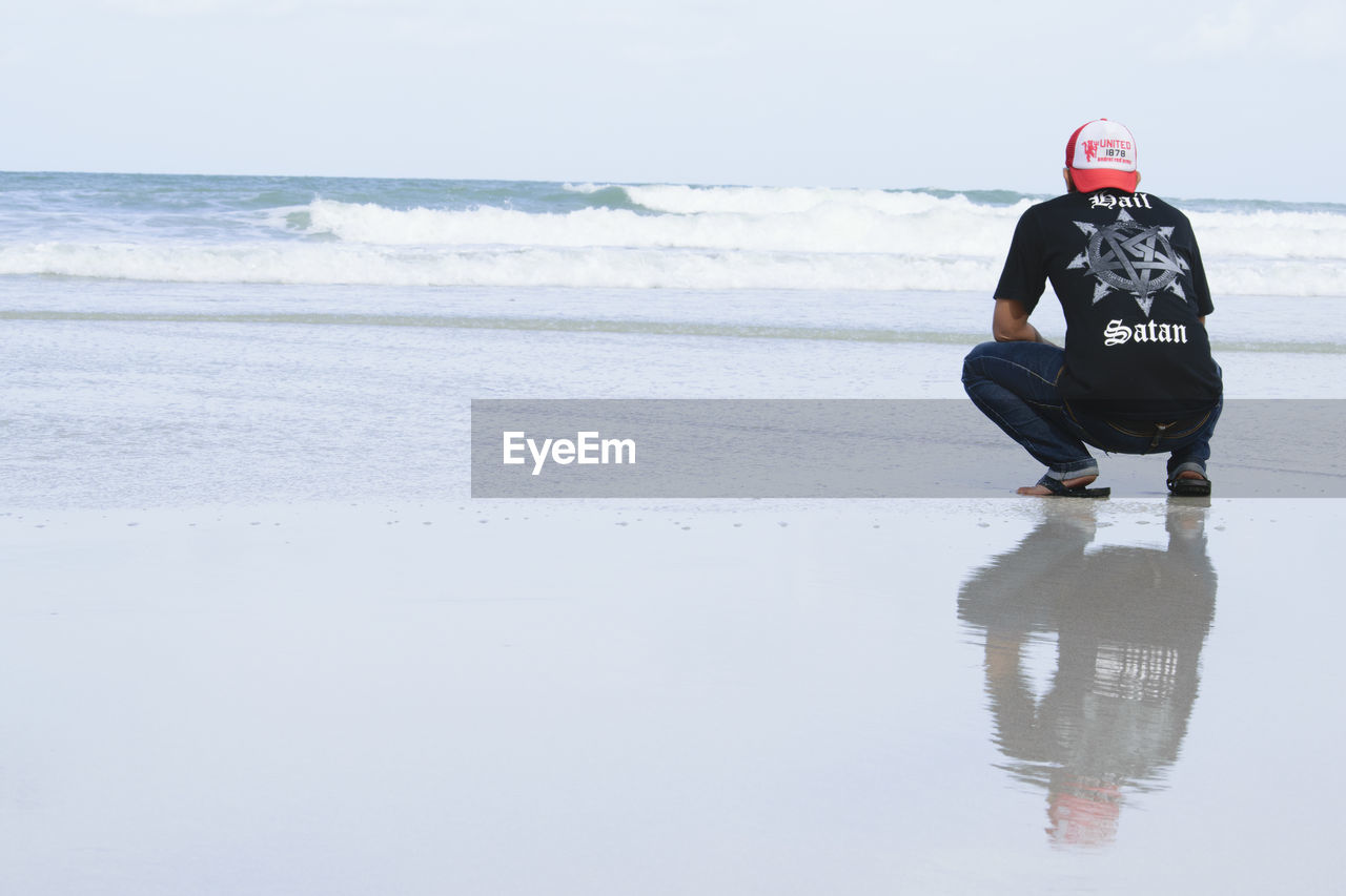 MAN AT BEACH AGAINST SKY