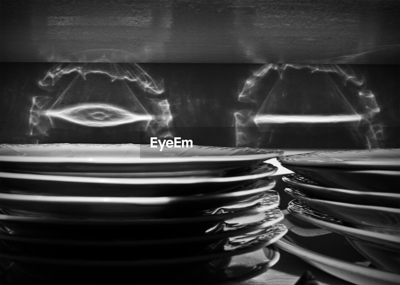 Close-up of plates stack in shelf with shadow