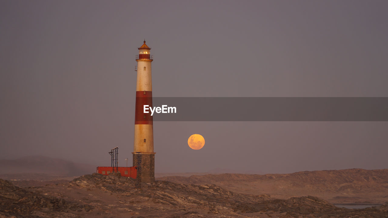 LIGHTHOUSE BY SEA AGAINST CLEAR SKY