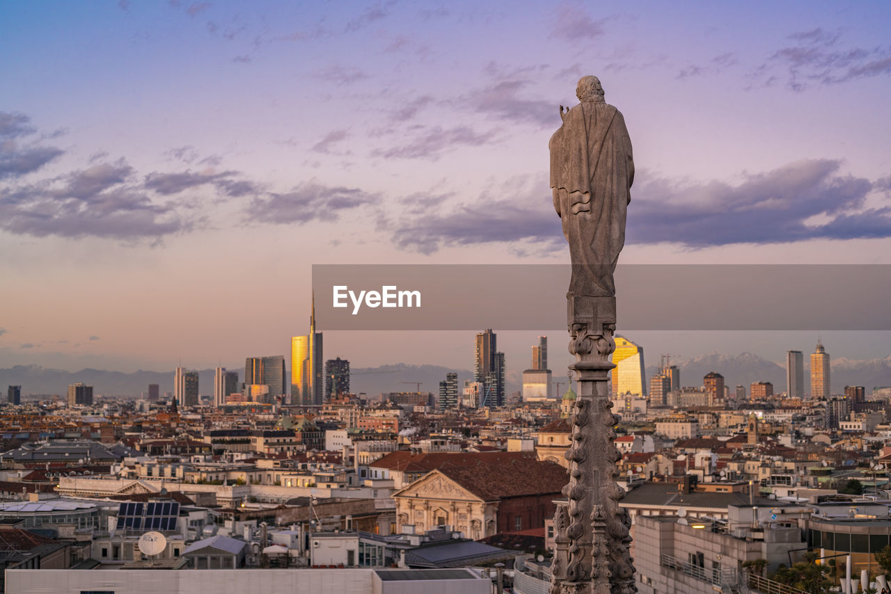 View of the statues on the cathedral of milan and the skyline of milan seen on the background