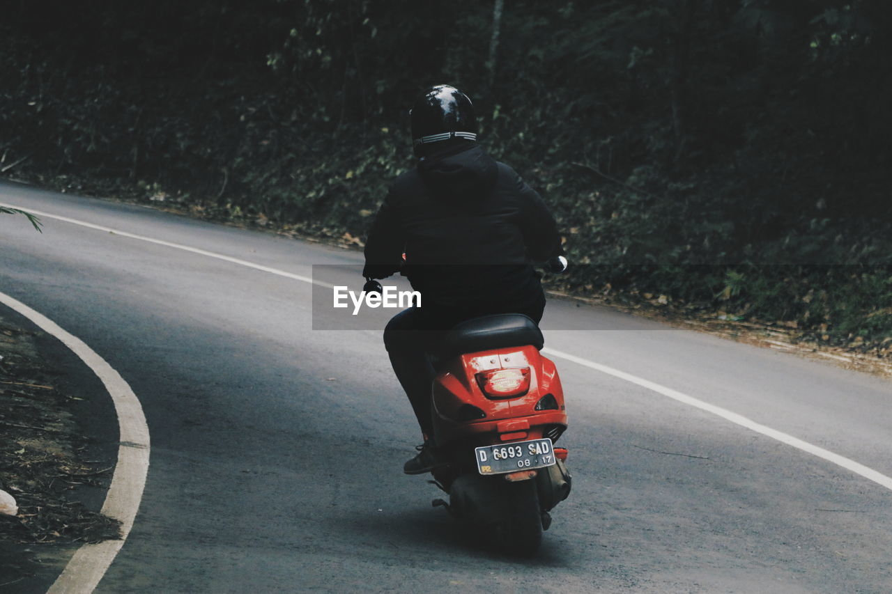 REAR VIEW OF MAN ON MOTORCYCLE ON ROAD