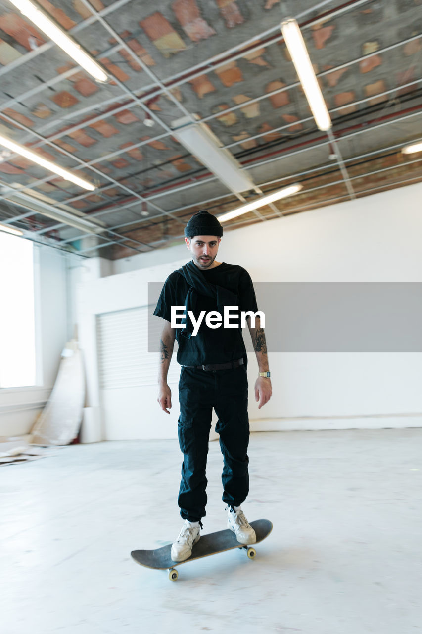 Portrait of young man standing on skateboard