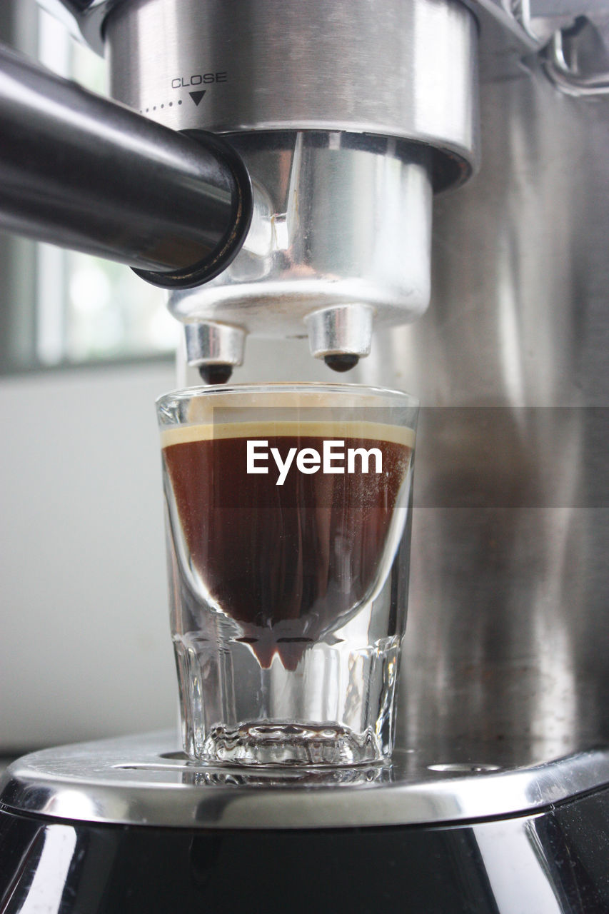 Close-up of pouring coffee in glass at cafe