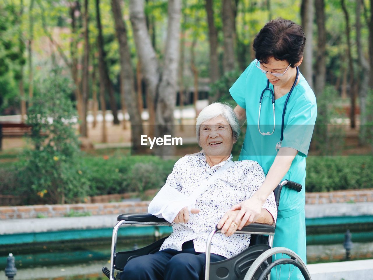 Nurse with female patient on wheelchair at park