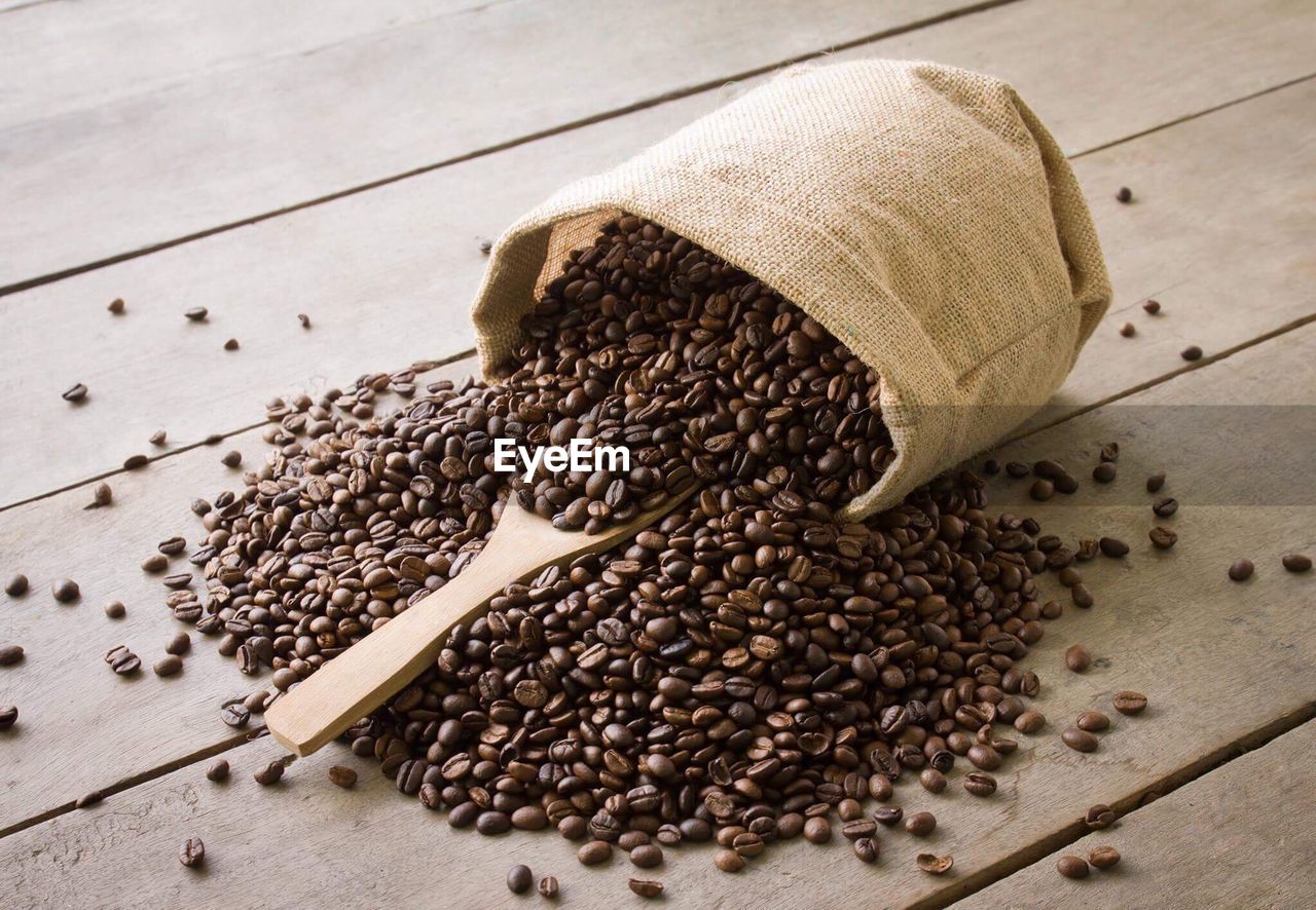 Roasted coffee beans spilling from sack on table