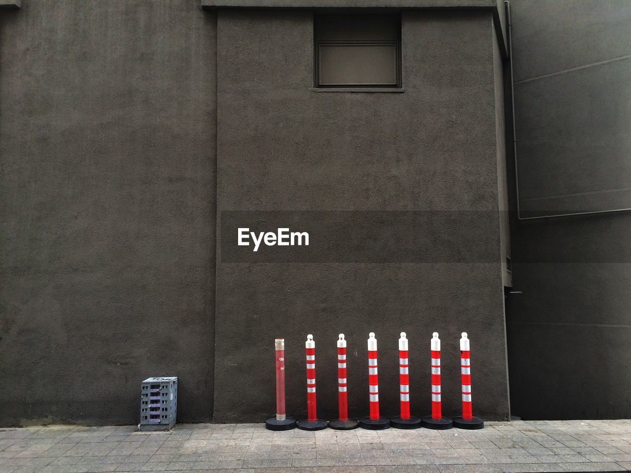 Reflective bollards on footpath against gray building