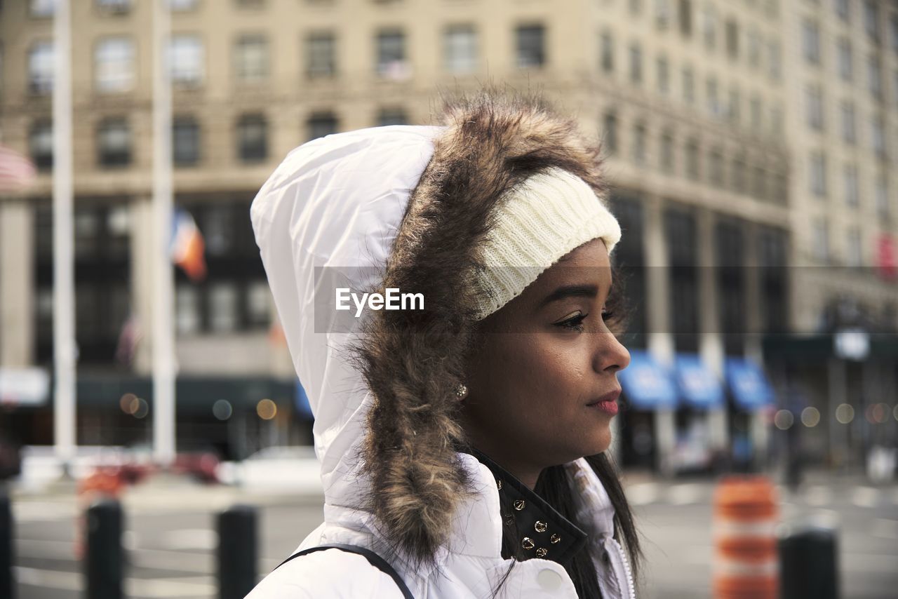 Side view of young african american female in outerwear walking along street in new york and enjoying stroll