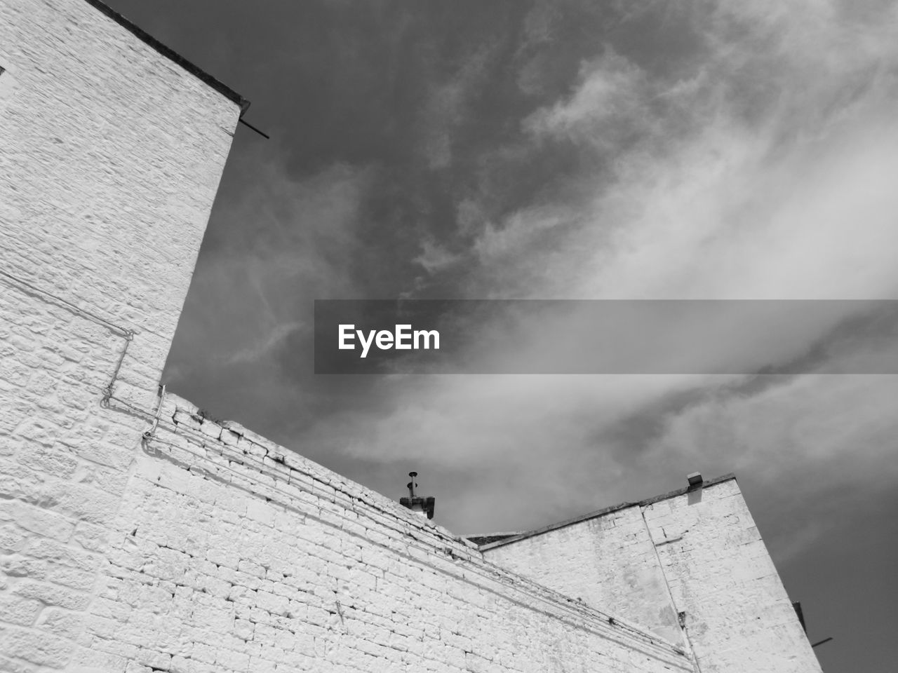 LOW ANGLE VIEW OF BUILDING AGAINST CLOUDS