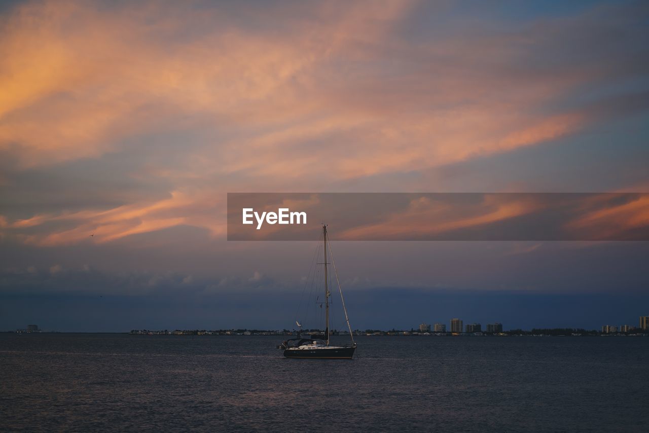 Sailboat sailing on sea against sky during sunset