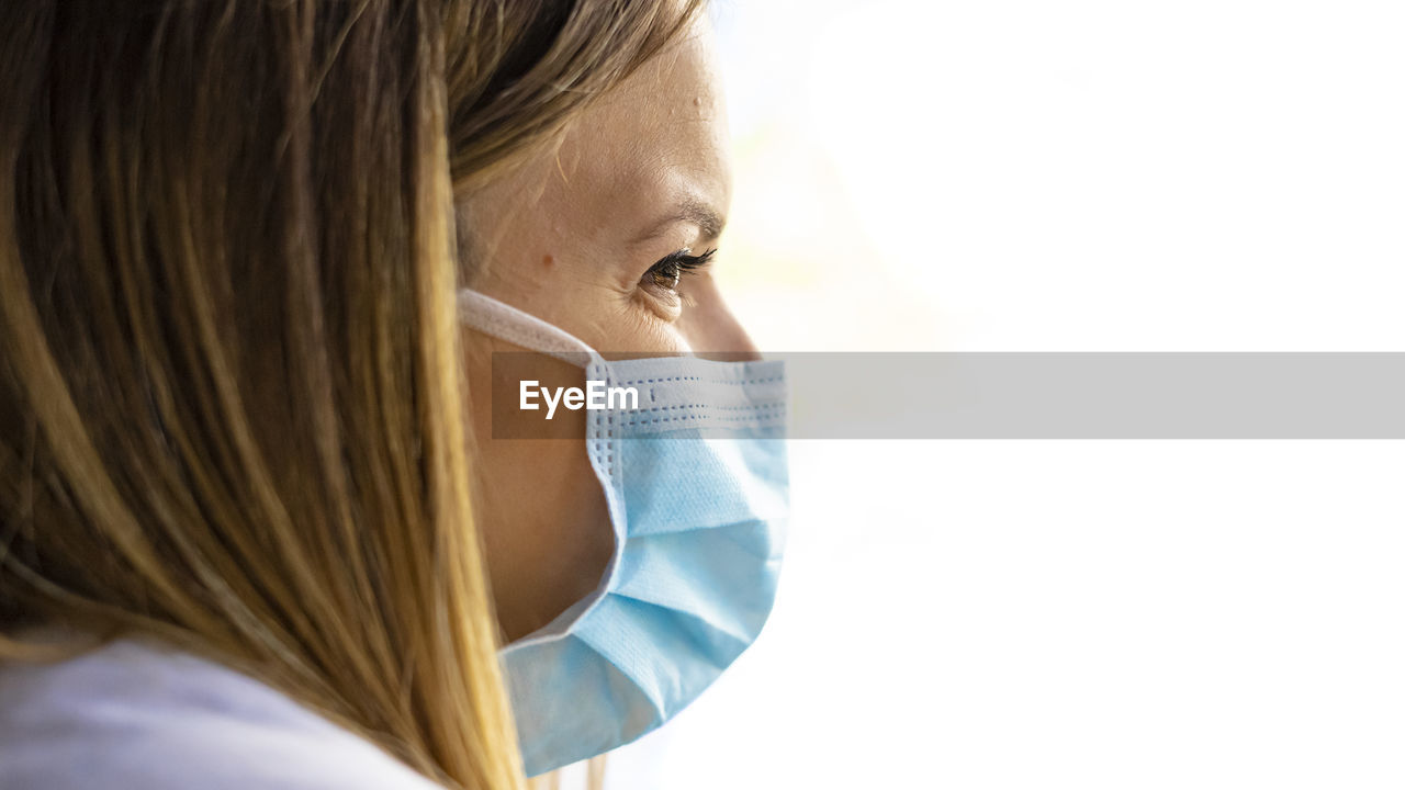 One woman, worried female doctor in protective suit, looking through the hospital window