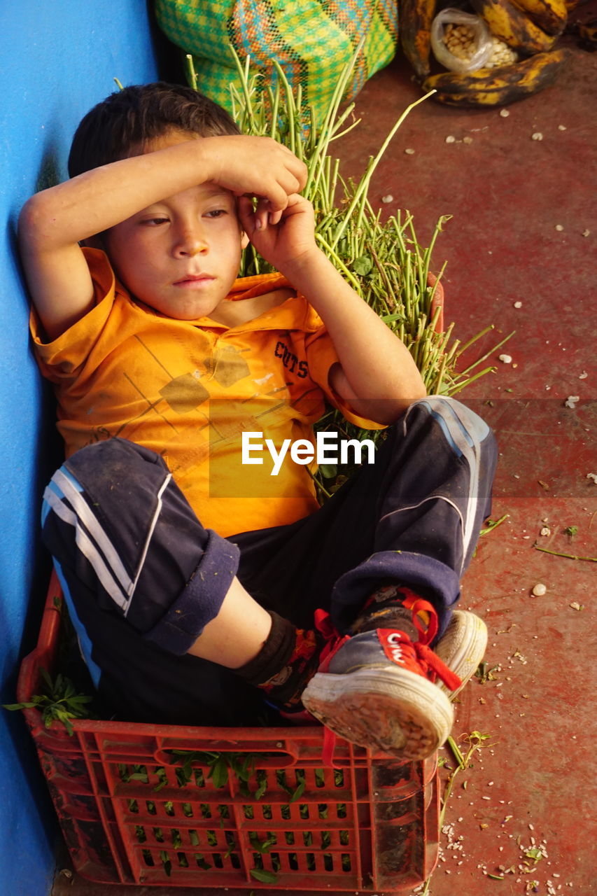 HIGH ANGLE VIEW OF CUTE BOY SITTING IN A PARK