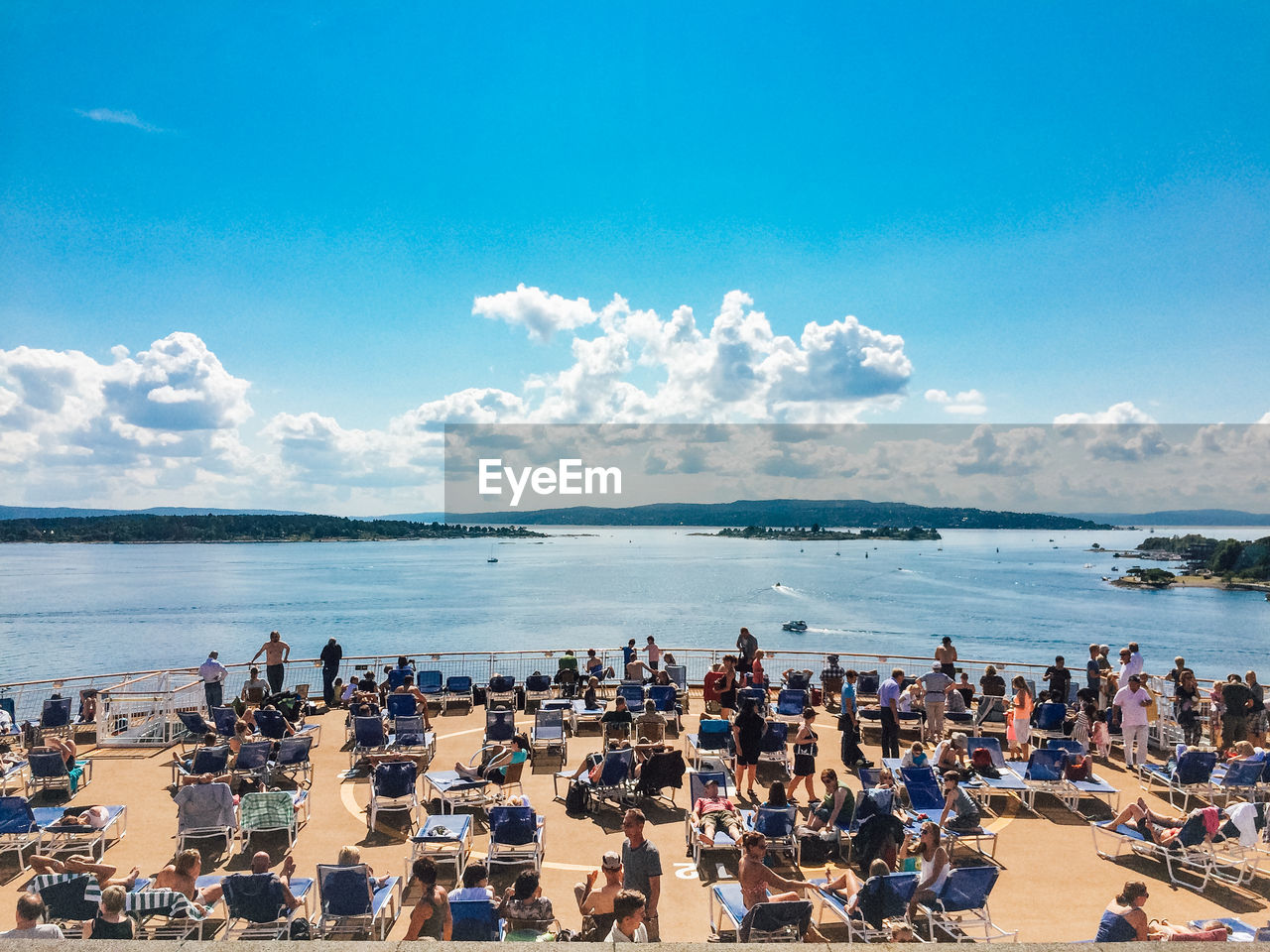 People at observation point by sea against sky