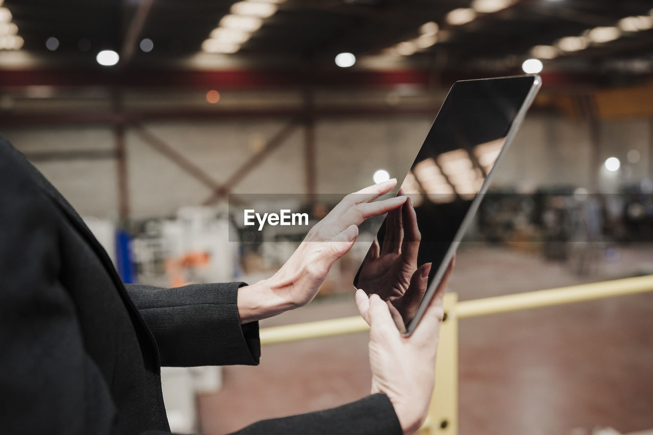 Hands of mature businesswoman using tablet computer at industry