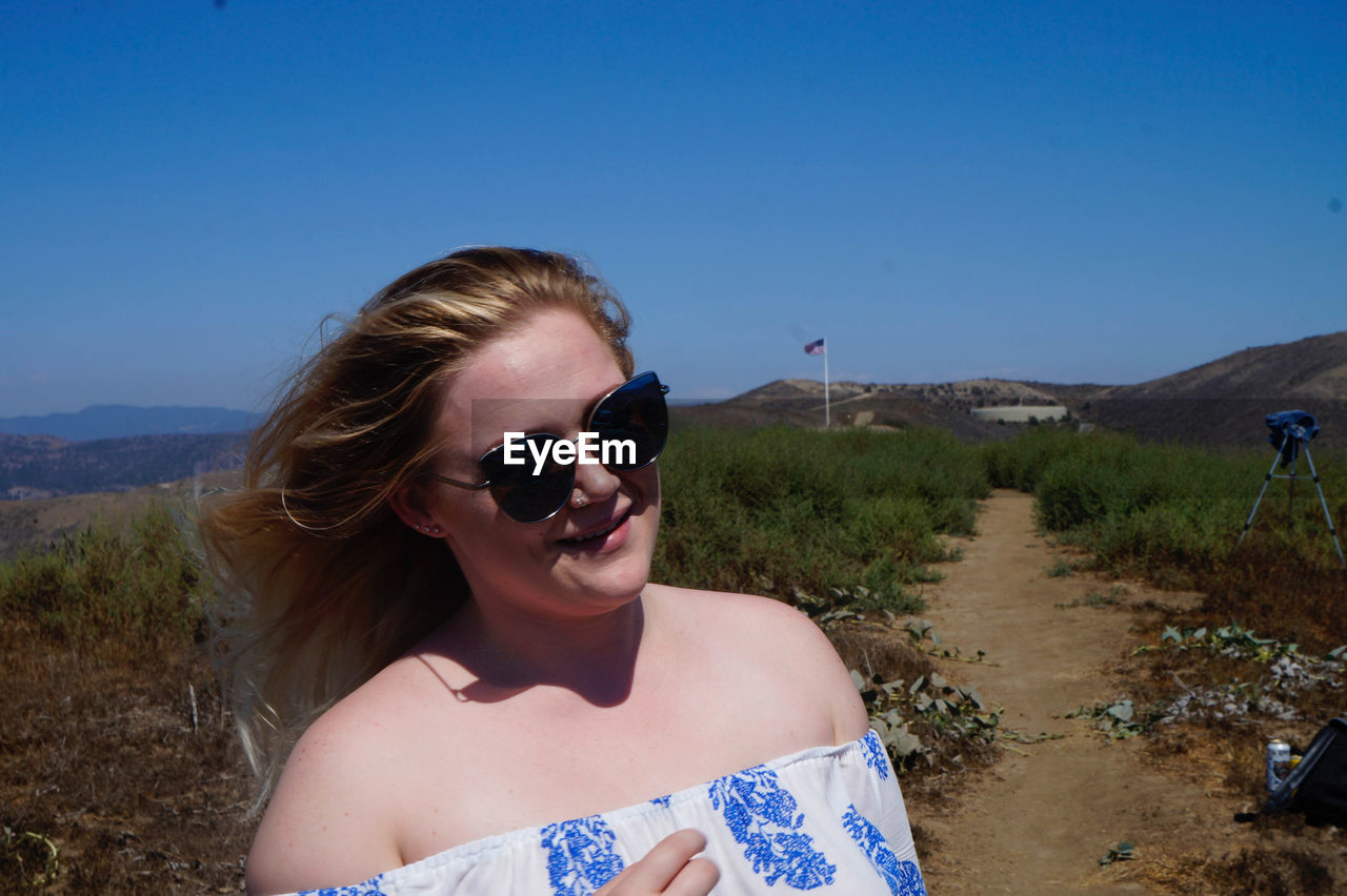 WOMAN STANDING ON MOUNTAIN AGAINST CLEAR SKY