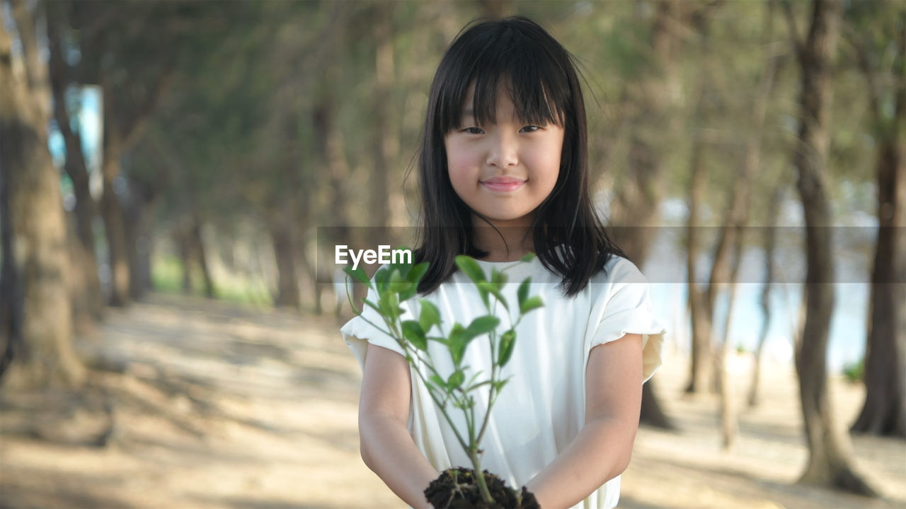 Portrait of woman standing against plants