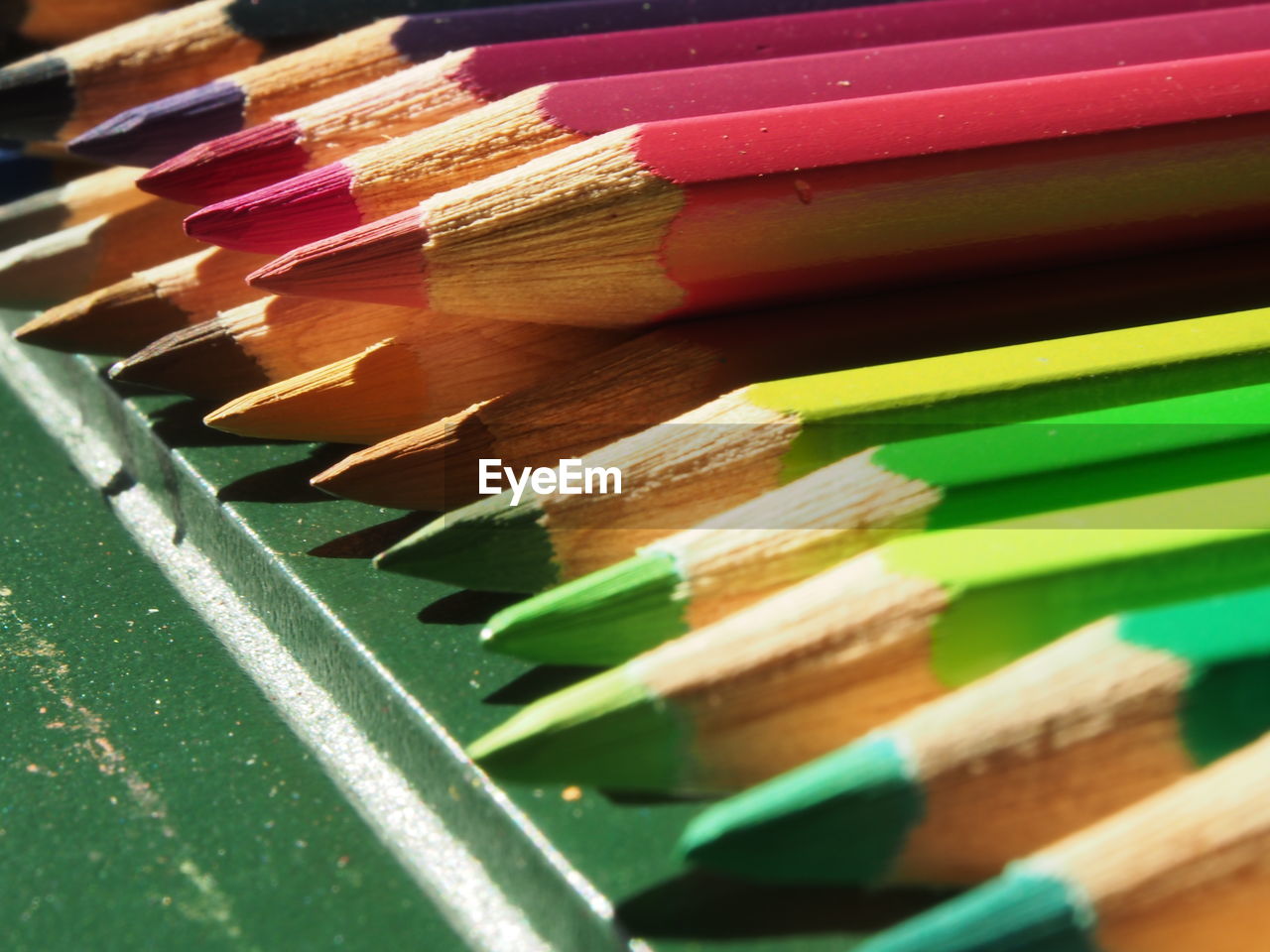 CLOSE-UP OF COLORED PENCILS ON WOOD