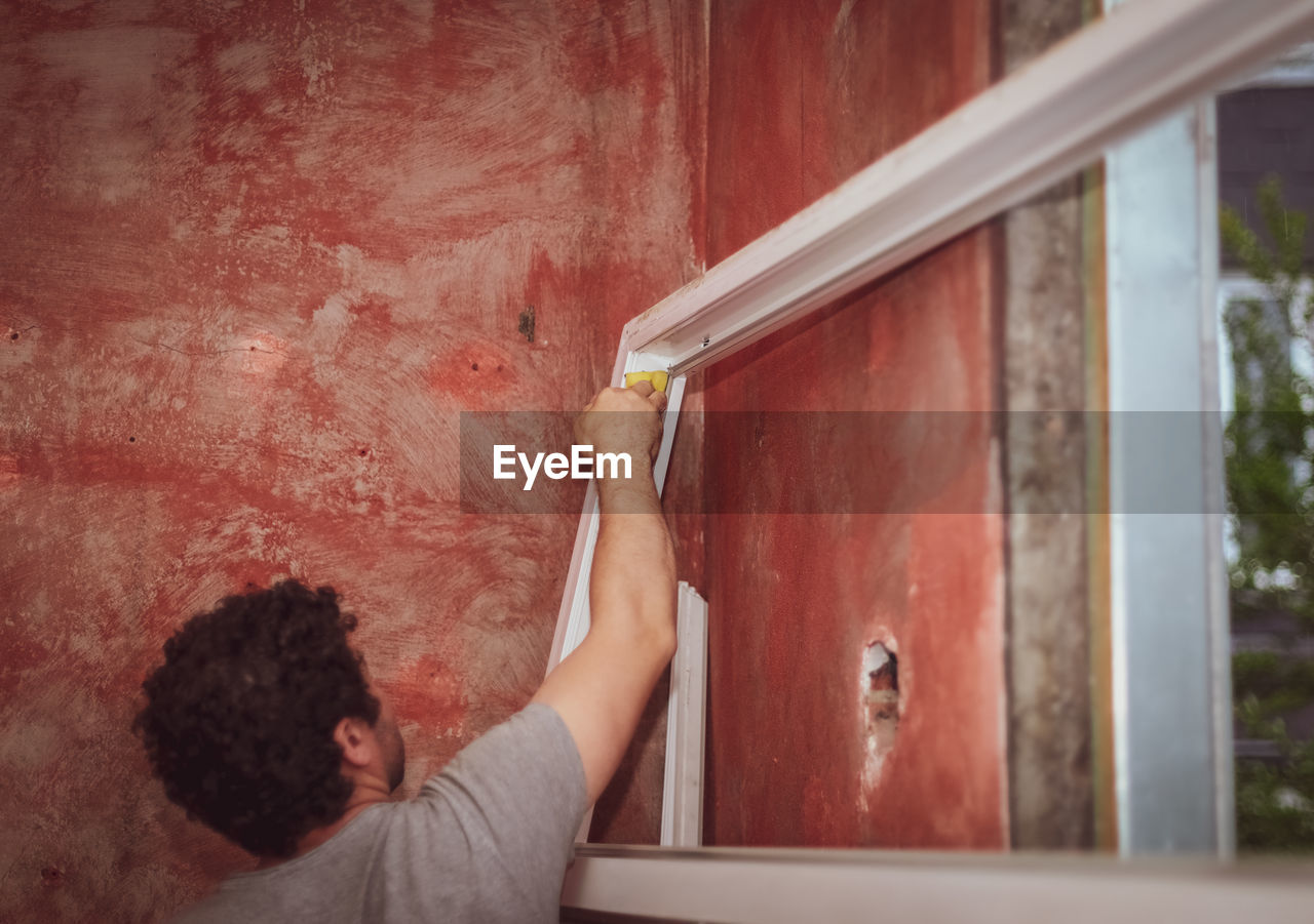 Caucasian male builder washes window frames with a sponge.