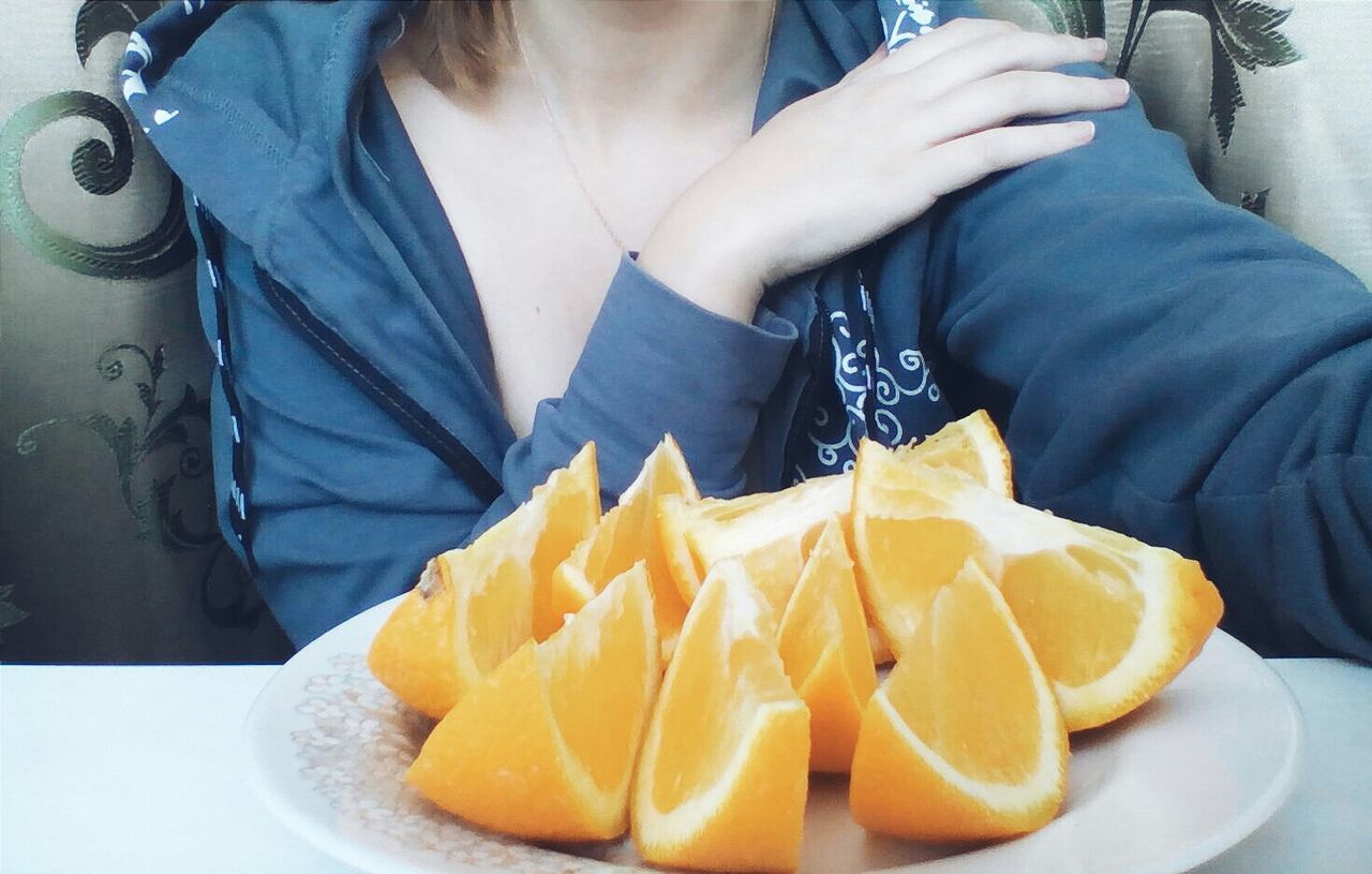 Close-up of woman eating orange slices in plate