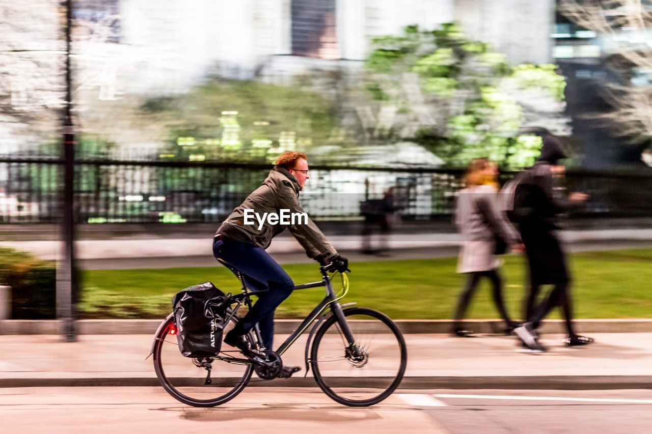 MEN RIDING BICYCLE ON STREET IN CITY