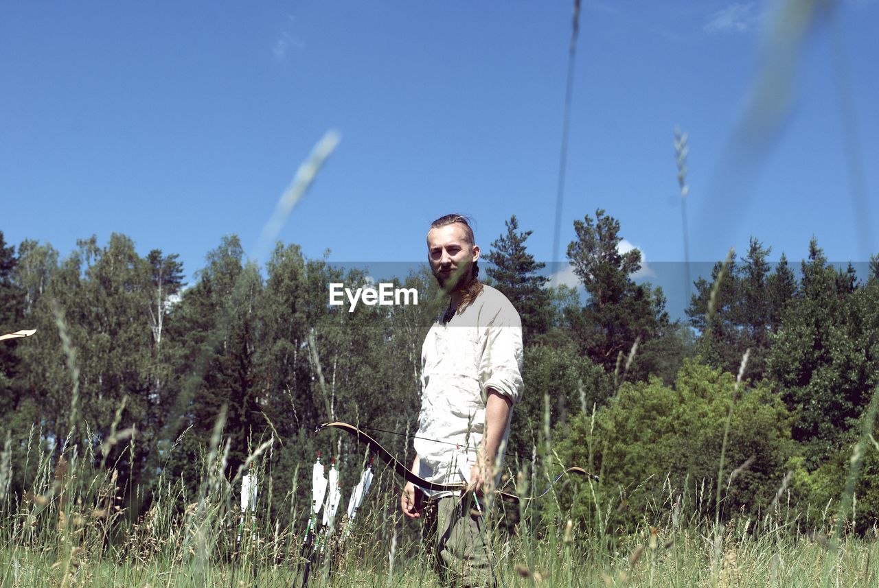 Full length portrait of young man standing against sky