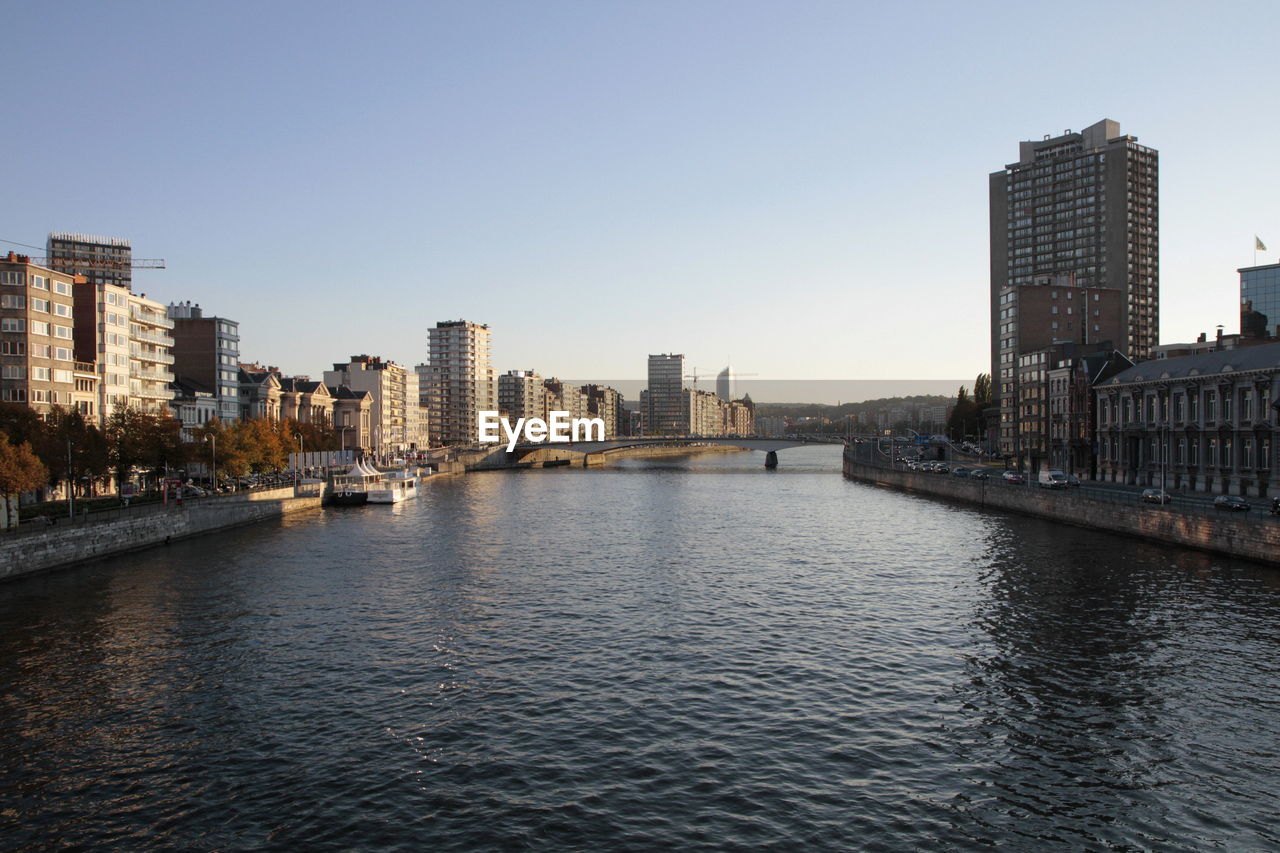 River amidst buildings in city against clear sky