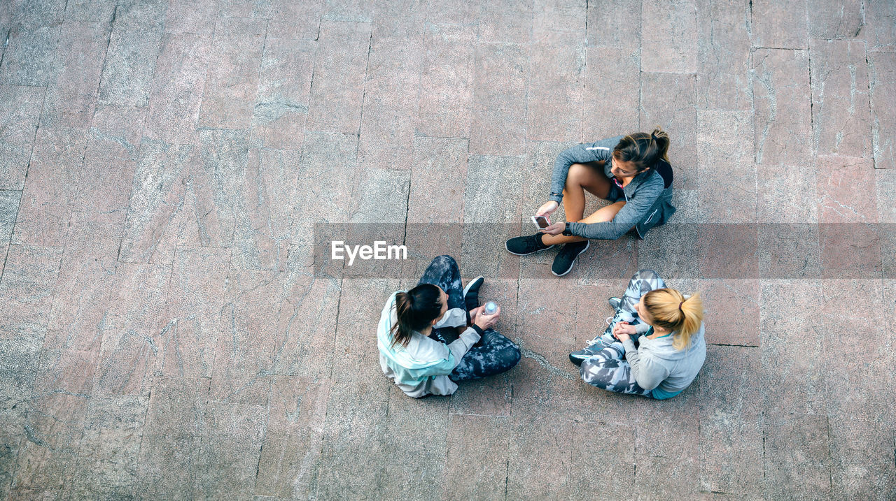 Women friends runners relaxing sitting on the floor after training