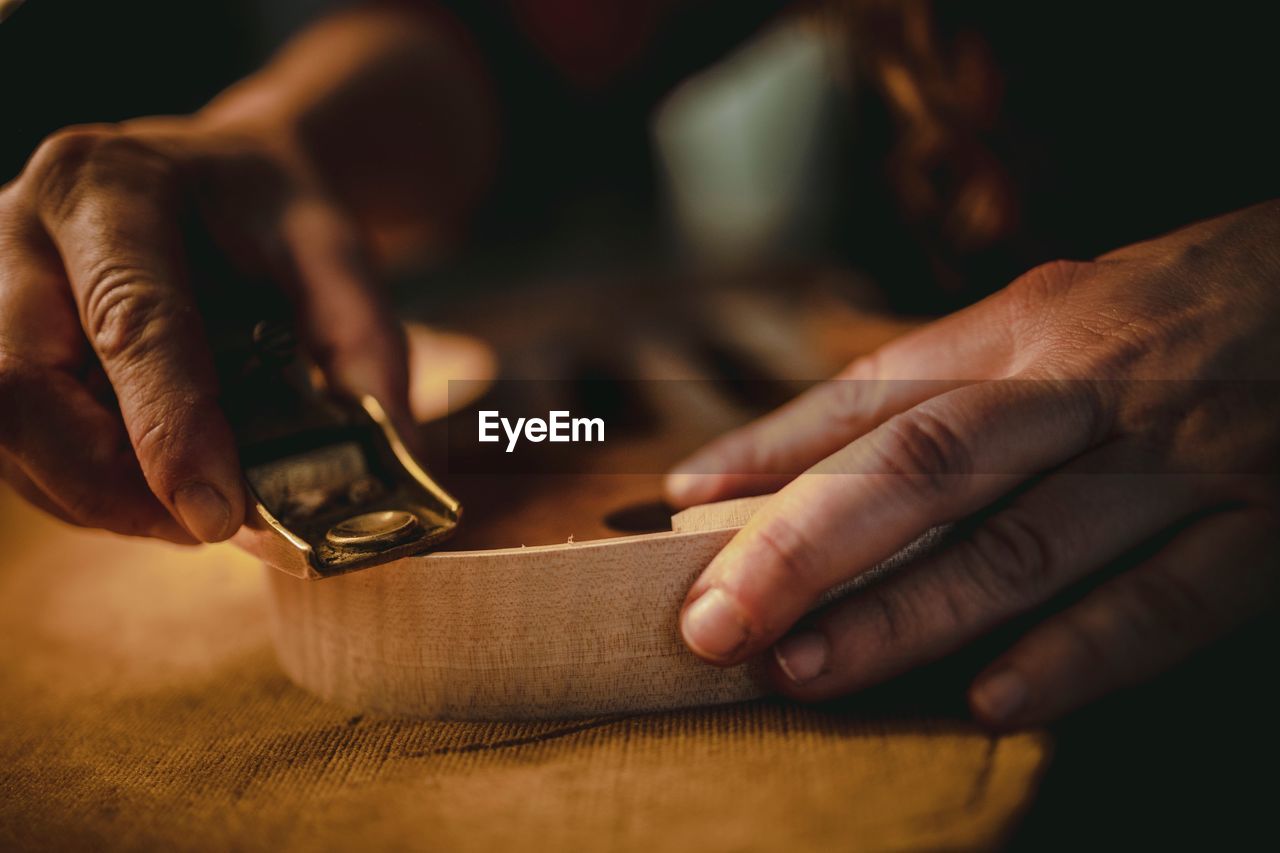 Cropped hand sharpening wood in workshop