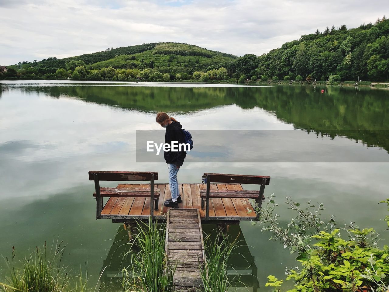 Girl standing by lake against sky