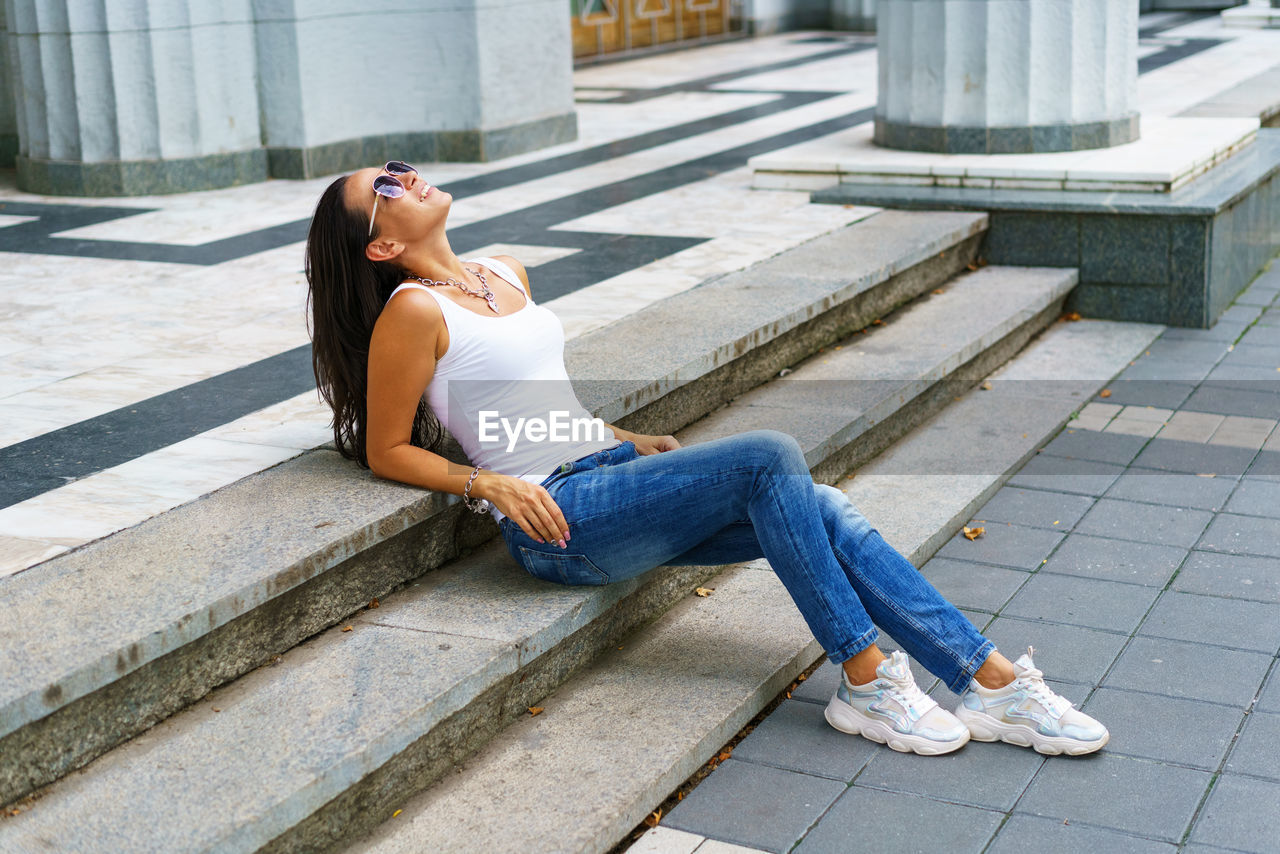 Casual style. stylish woman in sunglasses sitting on a stone staircase. she was
