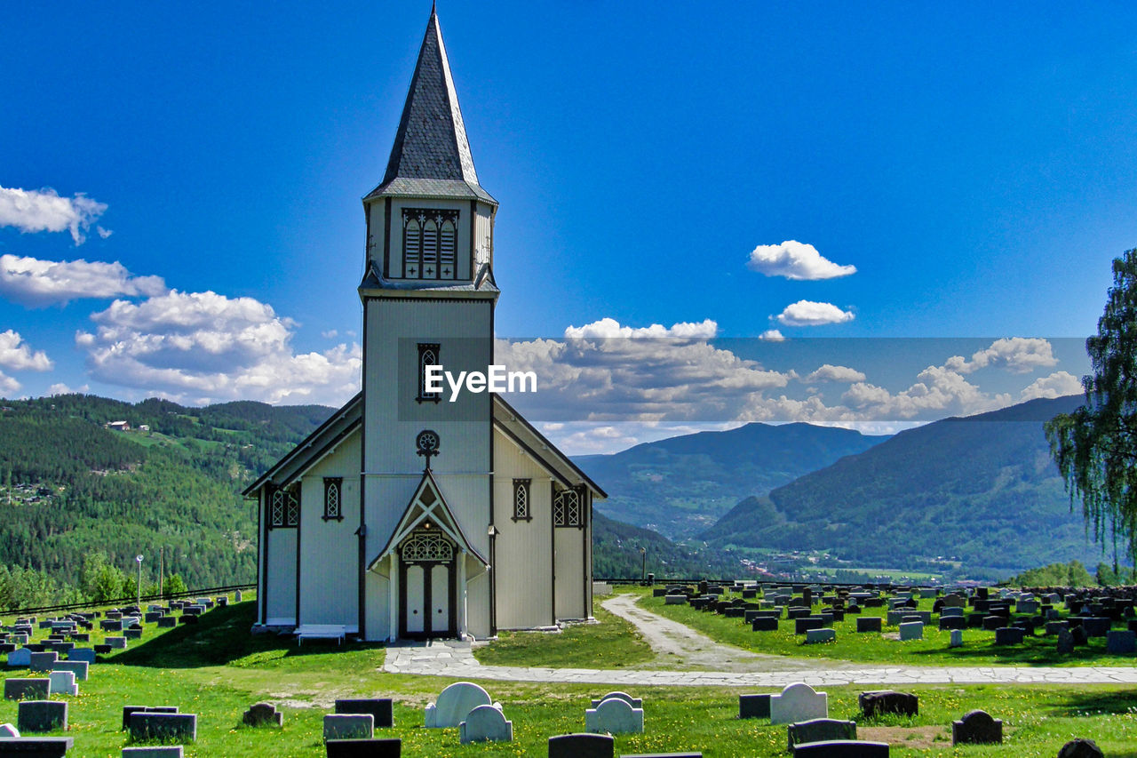 Clock tower amidst buildings and mountains against sky