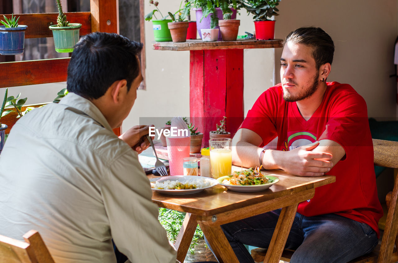 YOUNG MAN EATING FOOD IN RESTAURANT