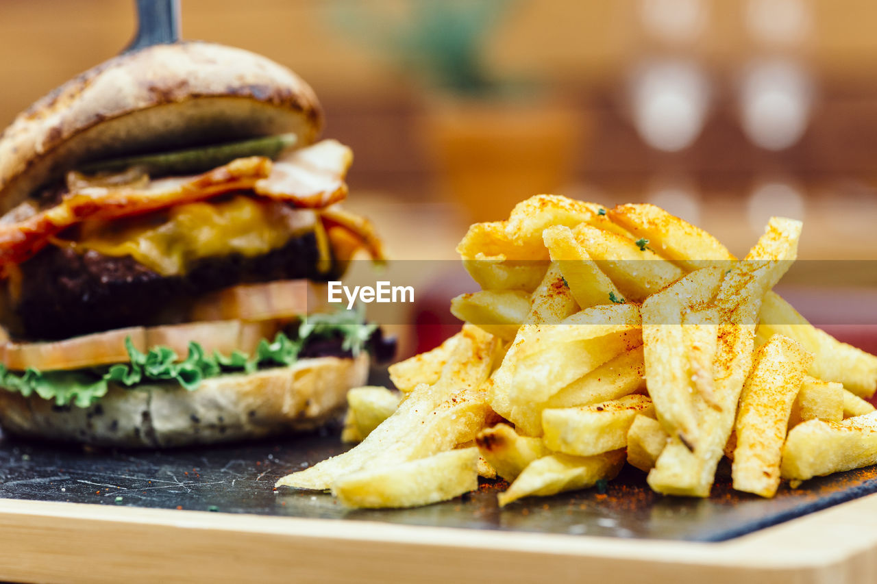 Close-up of french fries and burger served on table