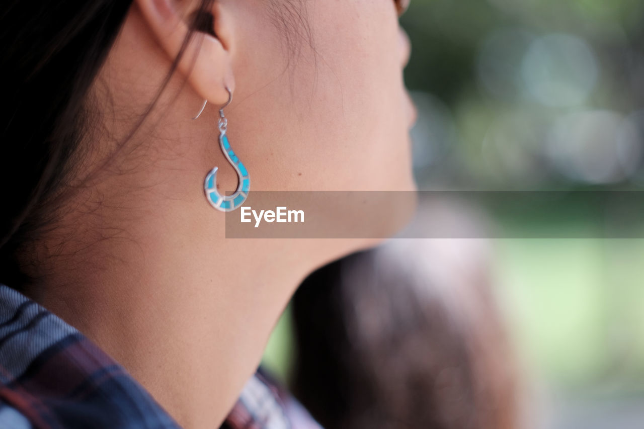 Cropped image of woman wearing blue earing