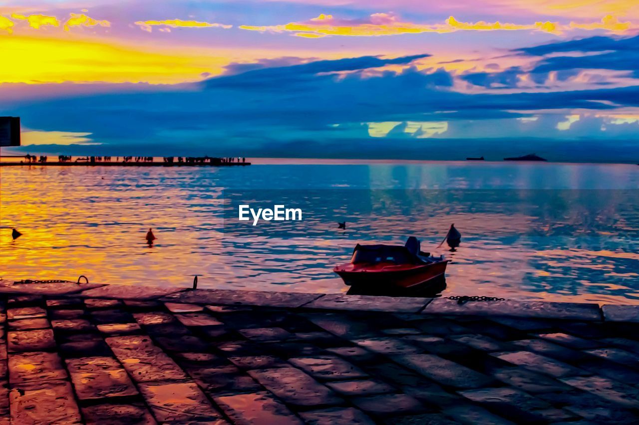 Boats moored in lake against sky during sunset