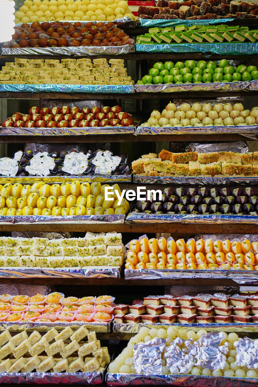 Various traditional, colorful indian sweets displayed at a tiny shop, india