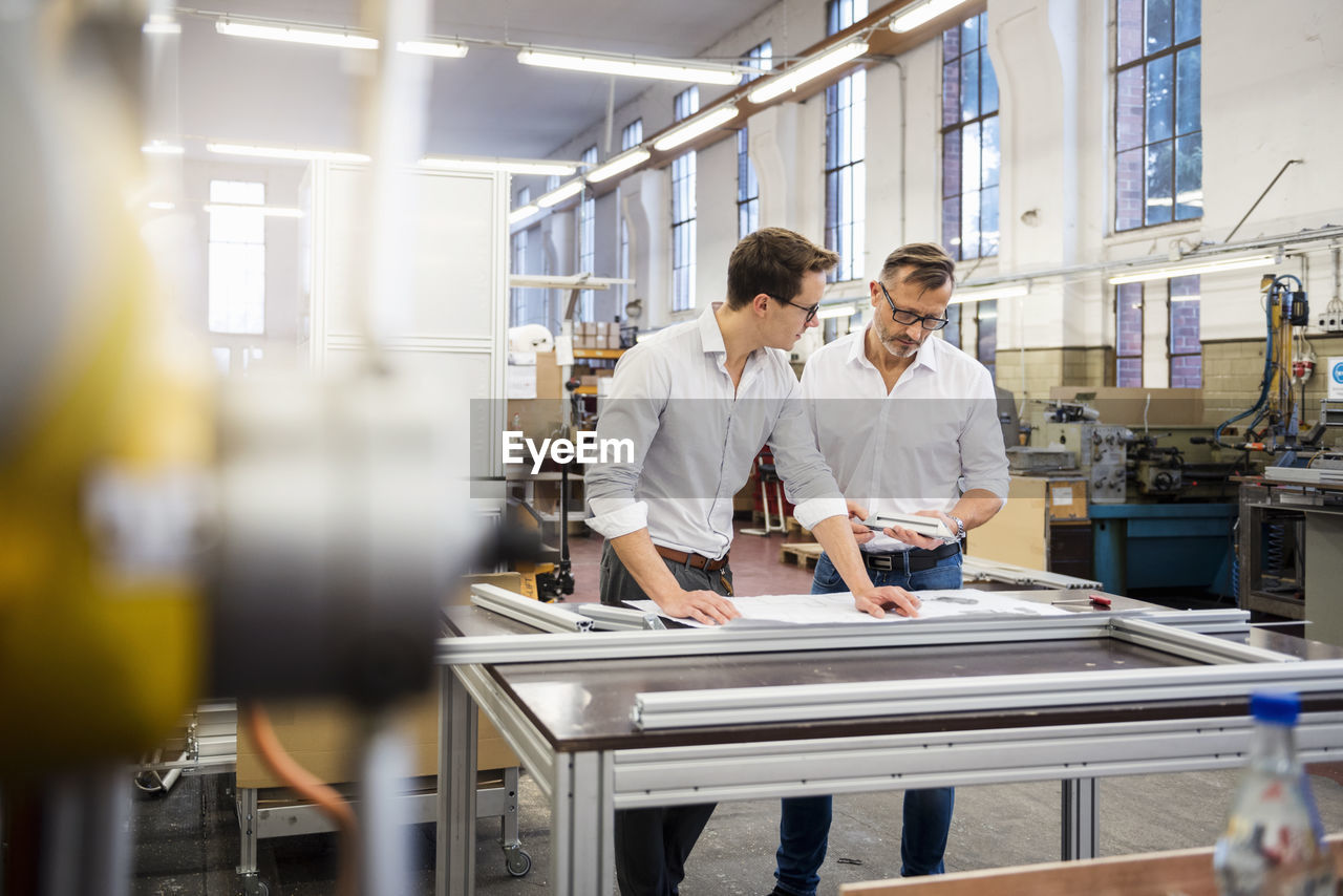 Two businessmen in factory discussing plan