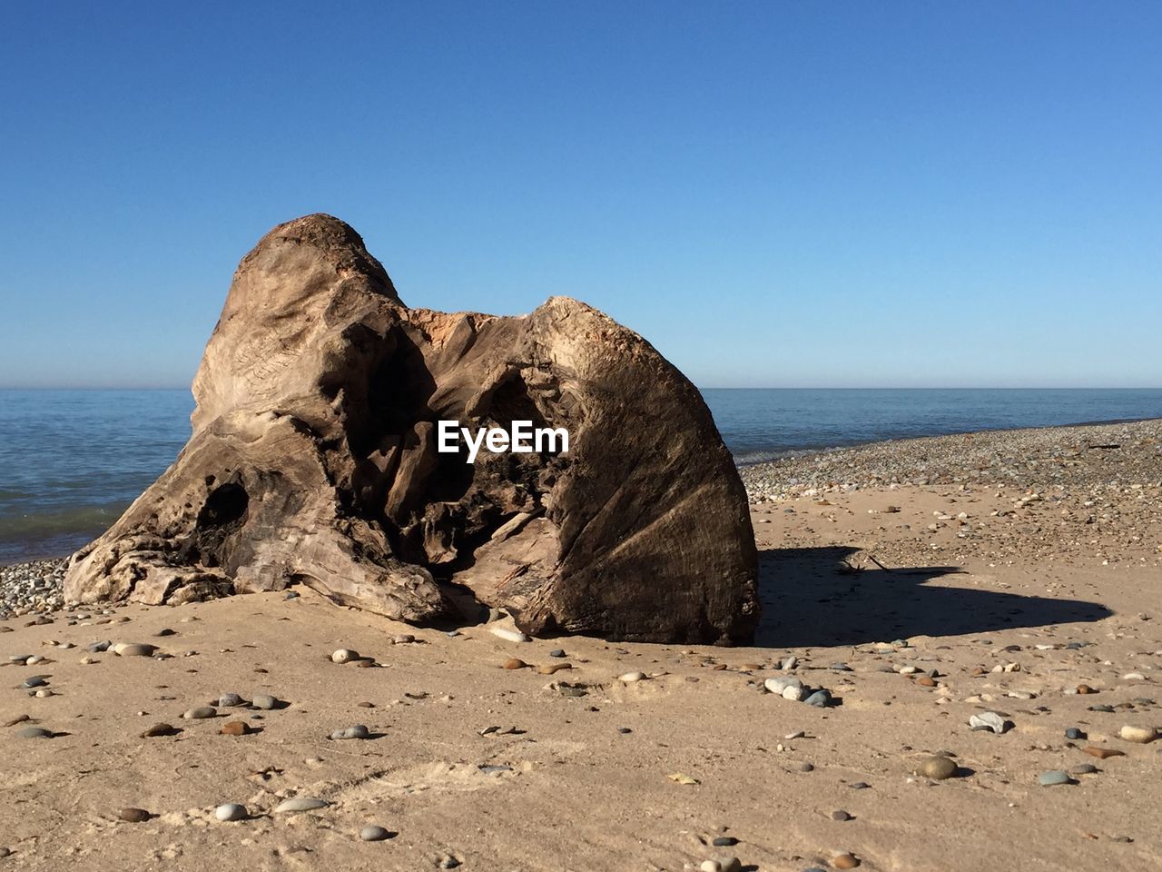 Rock formation on beach against clear blue sky