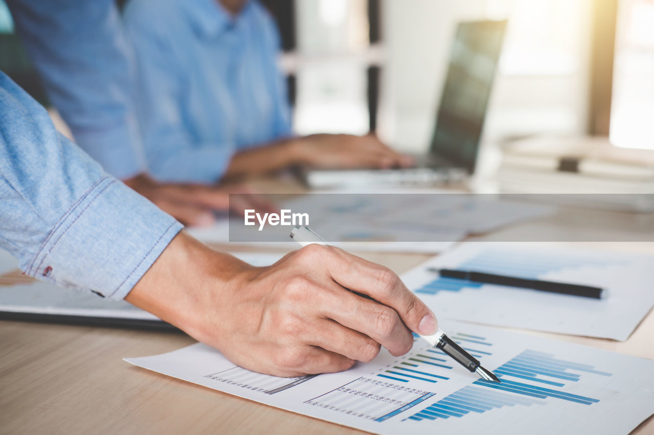 Cropped image of businesswomen working over graph in office