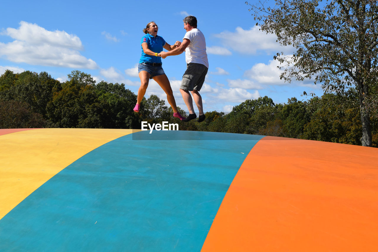 Low angle view of couple bouncing on castle against sky
