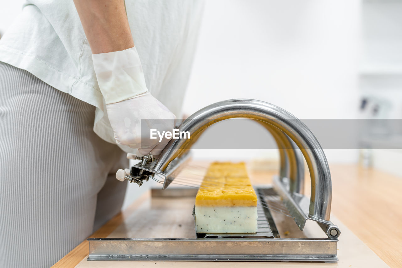 Midsection of man cutting soap in factory