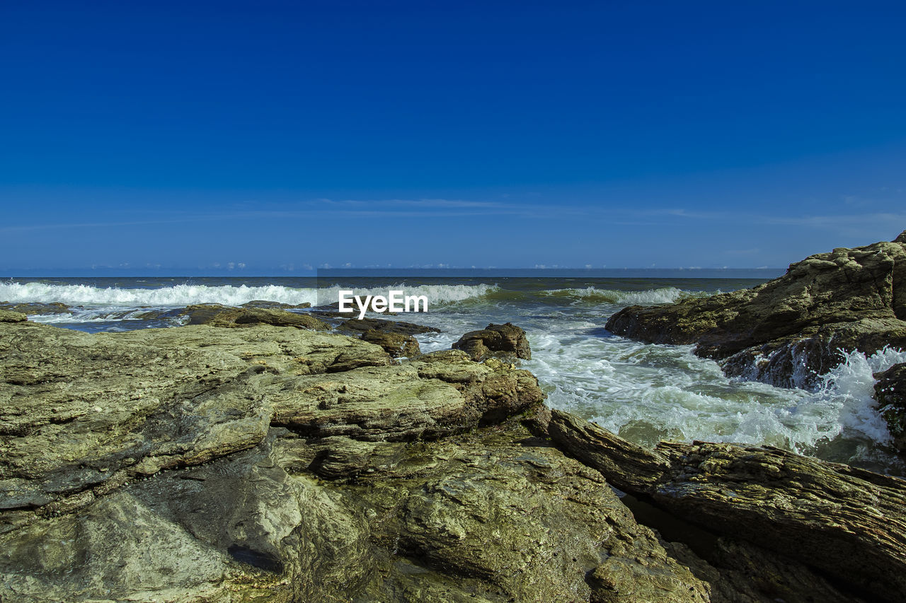 ROCKS ON BEACH AGAINST BLUE SKY