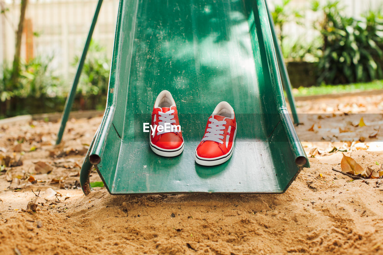 CLOSE-UP OF SHOES ON SWING AT PLAYGROUND